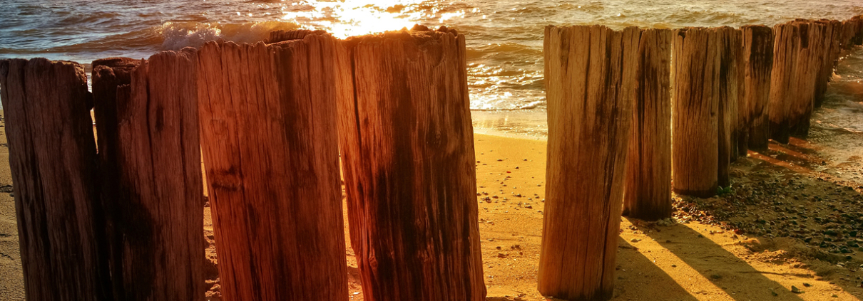 Holzpfosten am Meer bei Sonnenuntergang