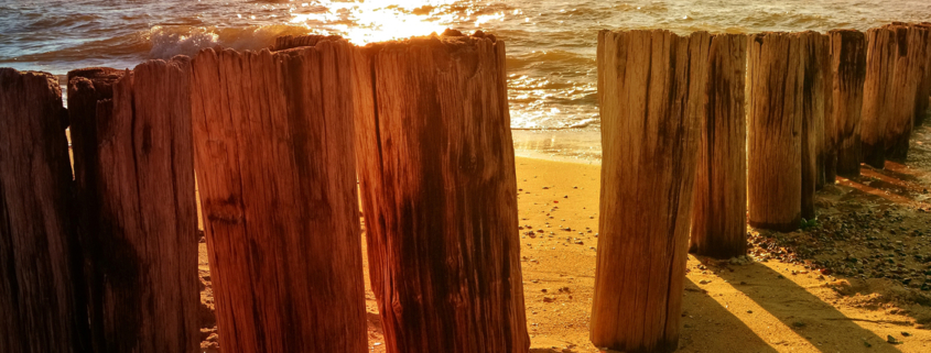 Holzpfosten am Meer bei Sonnenuntergang