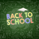 Slogan "Back to school" in bunten Kreidefarben auf grünem Tafelhintergrund mit kleinen Symbolen