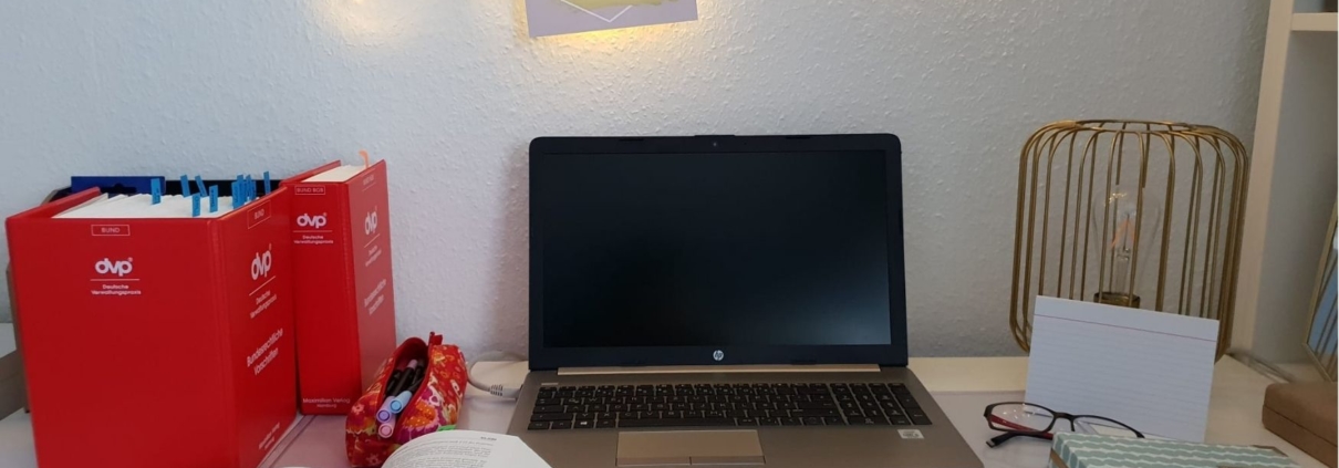 Blick auf einen Schreibtisch mit Laptop und Ordnern