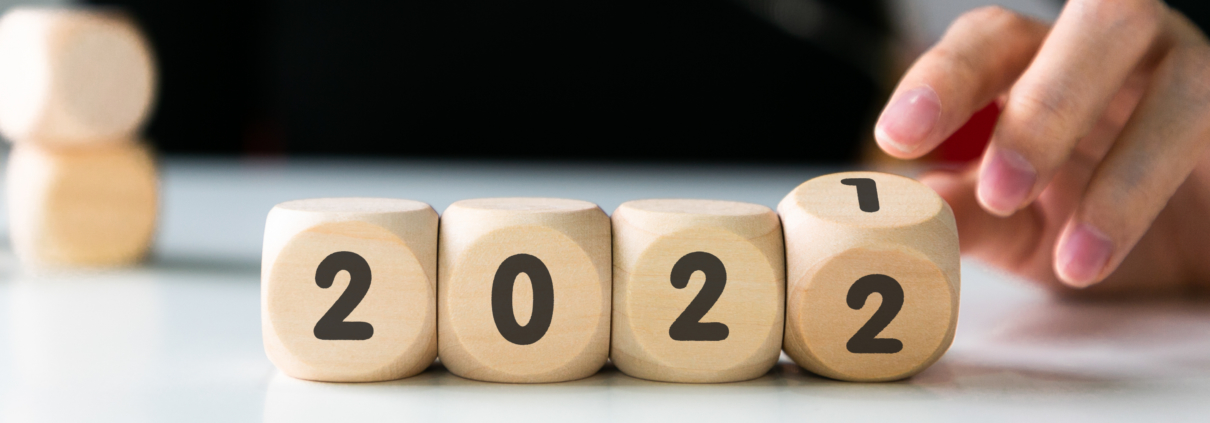 Vier Holzwürfel und eine Person, die den letzten Würfel von 2021 auf 2022 dreht