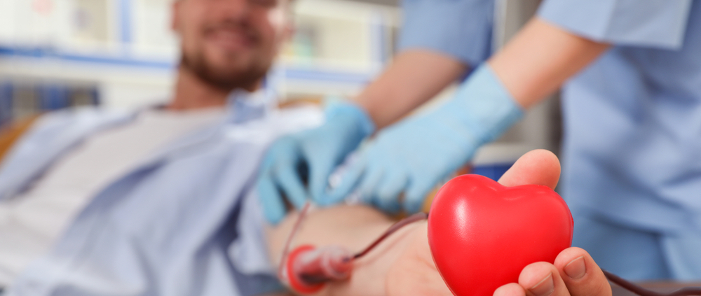 Ein männlicher Blutspender, der ein Plastikherz in der Hand hält