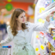 eine junge Frau nimmt etwas aus einem Supermarktregal