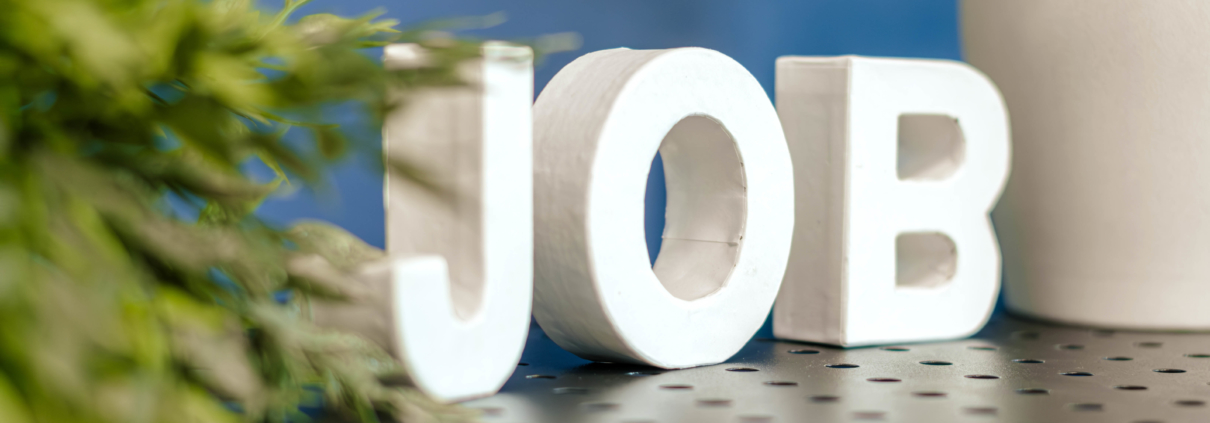 Das Wort Job steht in weißen Buchstaben vor blauem Hintergrund und Grünpflanzen