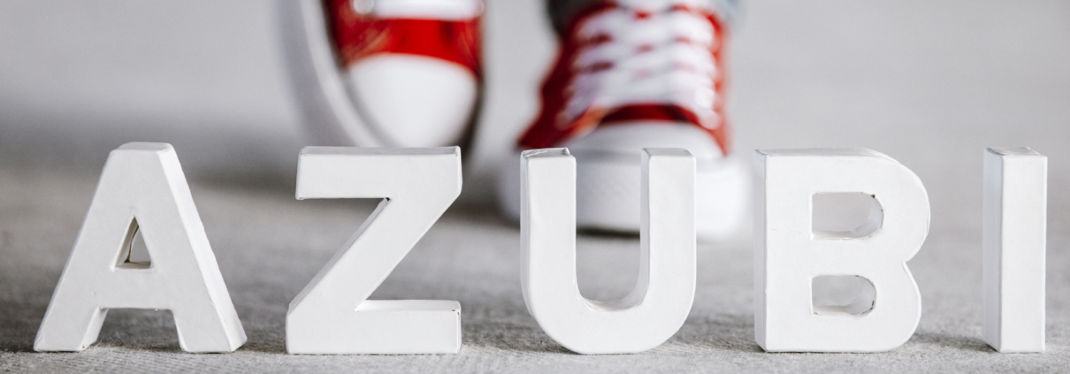 Das Wort Azubi steht in weißen Buchstaben vor roten Turnschuhen