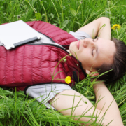 Junger Mann liegt entspannt mit geschlossenen Augen im Gras